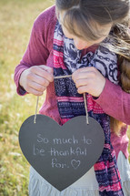 a child holding a sign that reads so much to be thankful for 