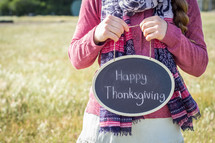 a girl holding a sign with the words Happy Thanksgiving 