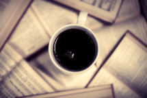 A cup of coffee rests on open books.