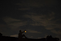 Man with the glow of a lantern under the starry sky