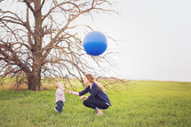 a mother and toddler boy with a balloon outdoors 