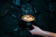 hand holding out a latte 