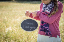 a girl holding a Happy Thanksgiving sign 