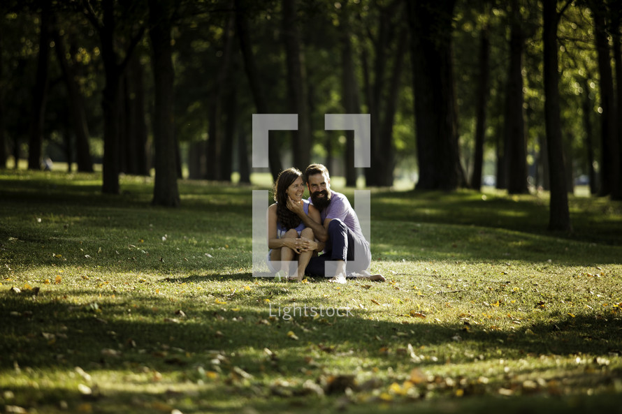 a couple sitting in grass in a park 