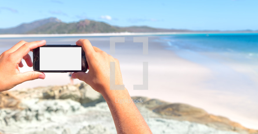 a person taking a picture of a beach with a cellphone 