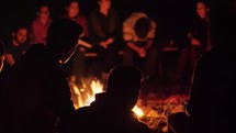 group of people sitting by a campfire 