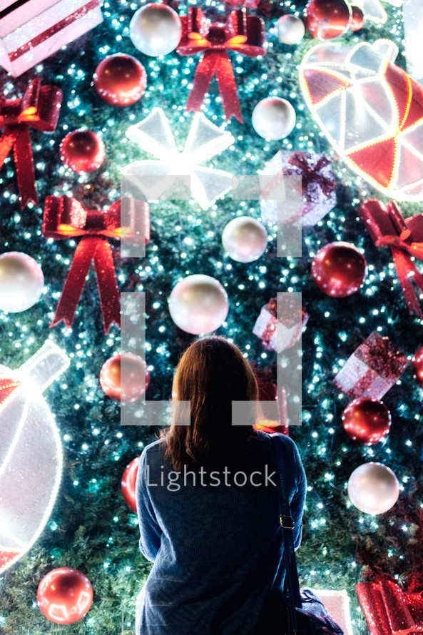 a woman looking at a Christmas light display 