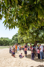 people gathered outdoors in a jungle village 