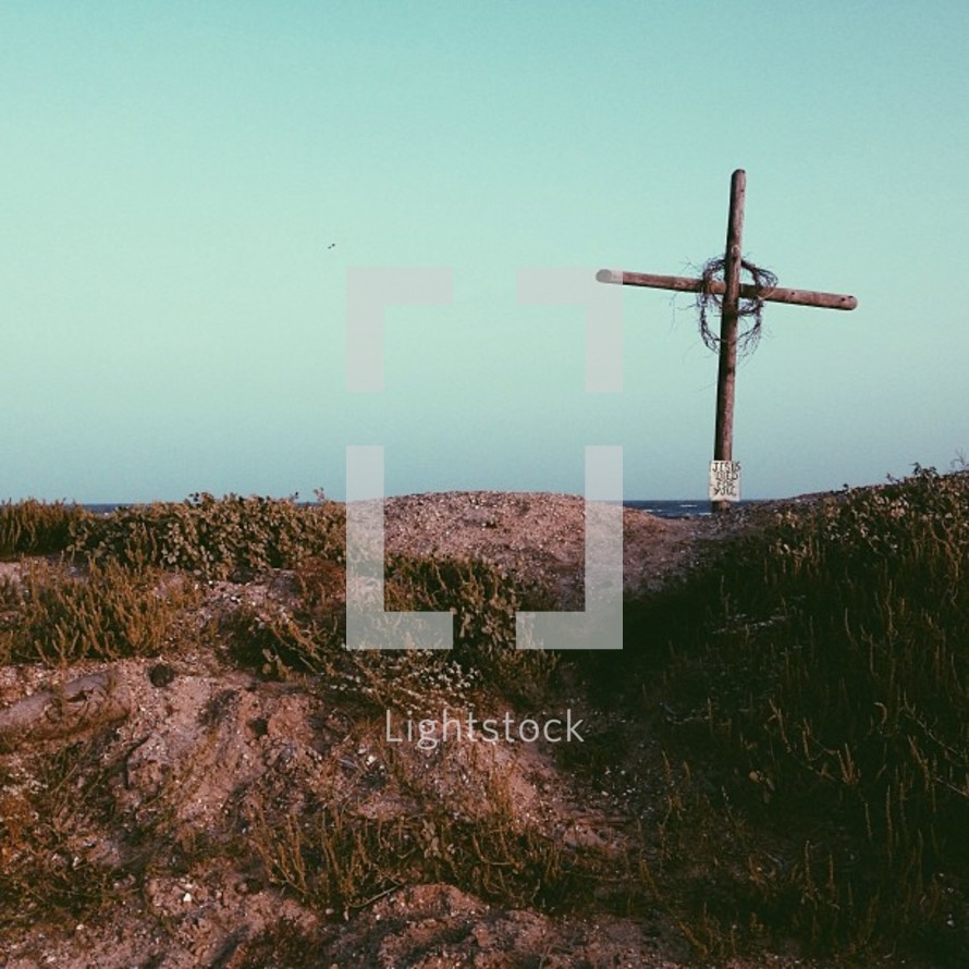 A wooden cross set atop a sand dune.