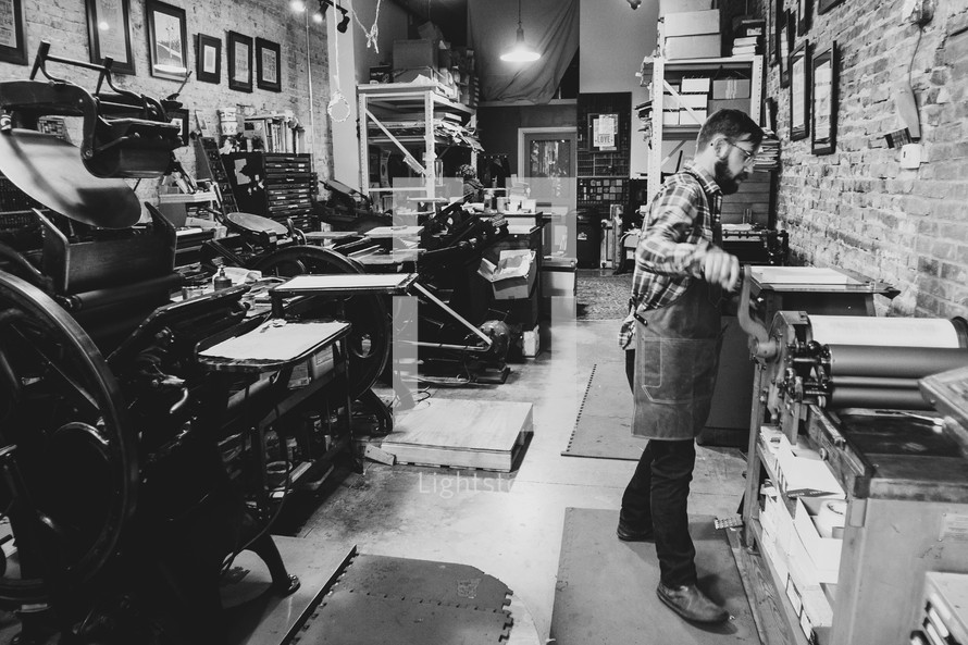 Man operating a letterpress machine in a downtown print shop