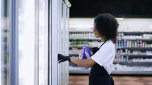 Portrait of supermarket worker opening the freezer with food to refill products.