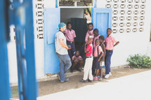 village children gathered outdoors with missionaries in a doorway 