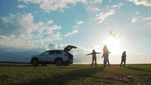 Silhouette the happy family. Four people, mother, father and two children are happy standing near the open trunk of a car at the sunset time. Concept of summer vacation and friendly family.