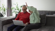 Mature couple sitting on couch and having video conference with their family on laptop.