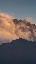 Misty clouds motion fast over alps mountains peak at sunset, Vertical video Timelapse
