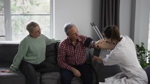 Woman therapist measuring blood pressure of senior man at home.