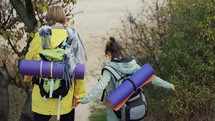 Couple hikers walk in forest park with backpacks, crawling through the bushes.