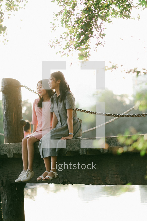 girls sitting on a bridge 