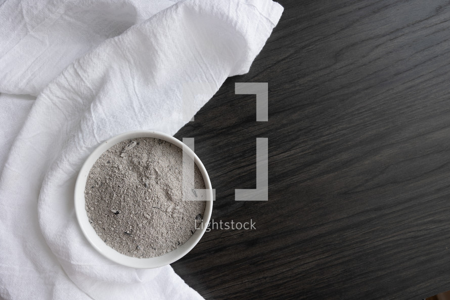 white linen and bowl of ashes on a wood background 