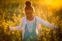 a little girl walking through a field of yellow flowers 