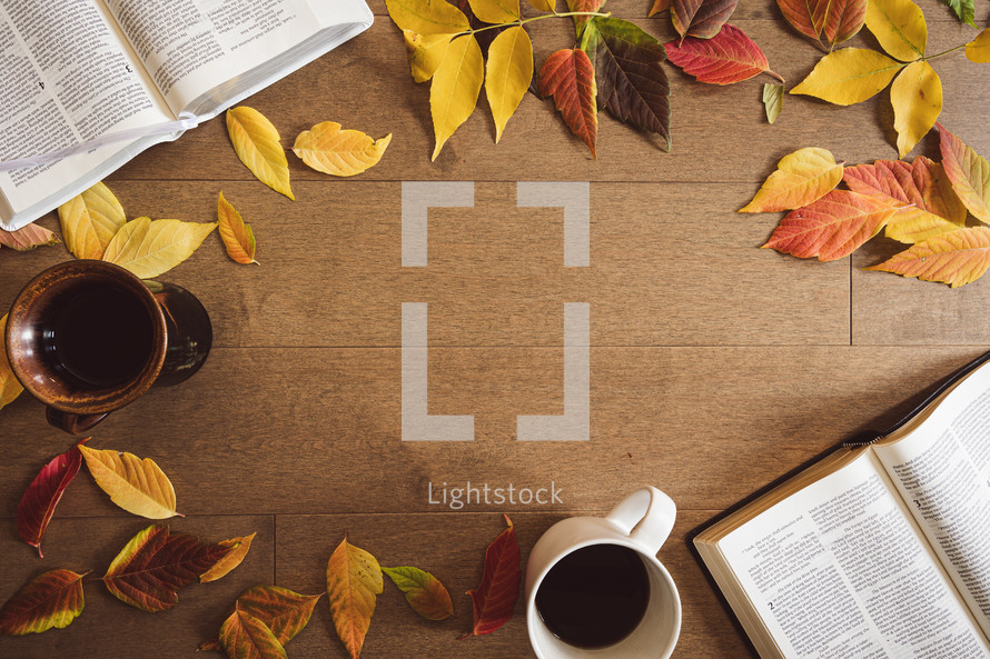 Open bibles, coffee cups and autumn leaf frame on a wood background with copy space