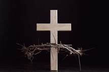 Wooden cross with crown of thorns on a black background