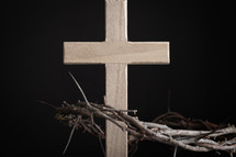 Wooden cross with crown of thorns on a black background