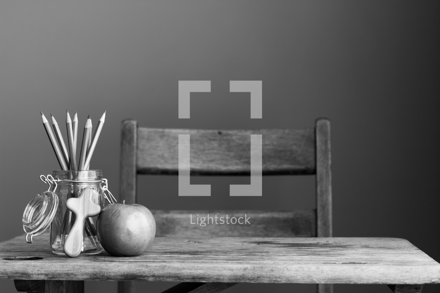 student desk with apple and wooden cross 