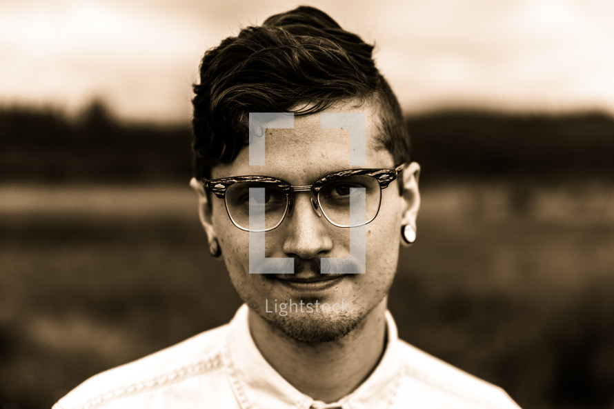 face of a man with ear gauges and glasses 