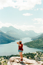 woman over looking a mountain lake standing on a cliff 