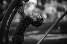 a boy child climbing monkey bars on a playground 