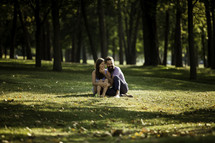 a couple sitting in grass in a park 