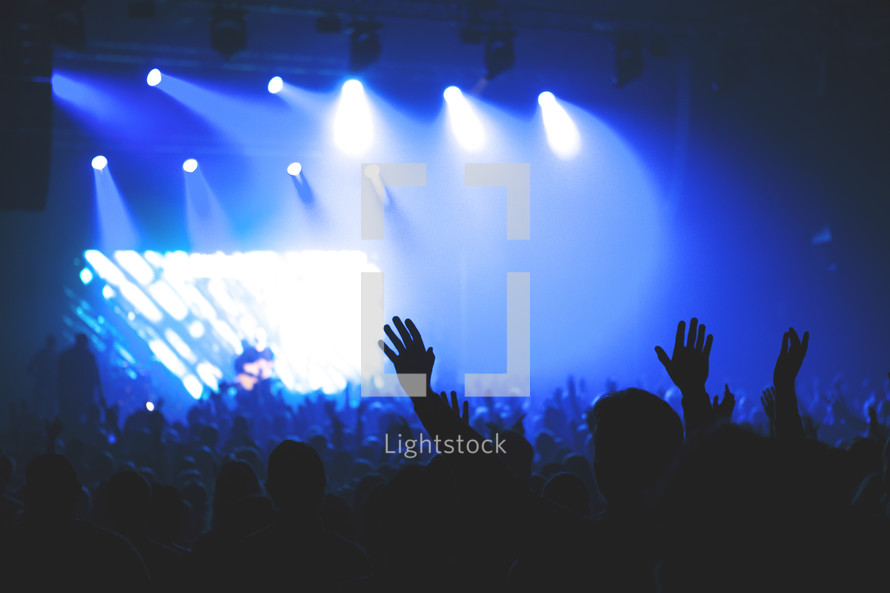 spotlights shining on crowds at a concert 