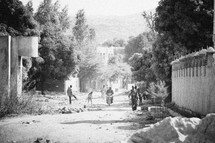 A group of men and boys walk down a dirt road.