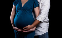 torso of an expecting woman and man holding her belly 