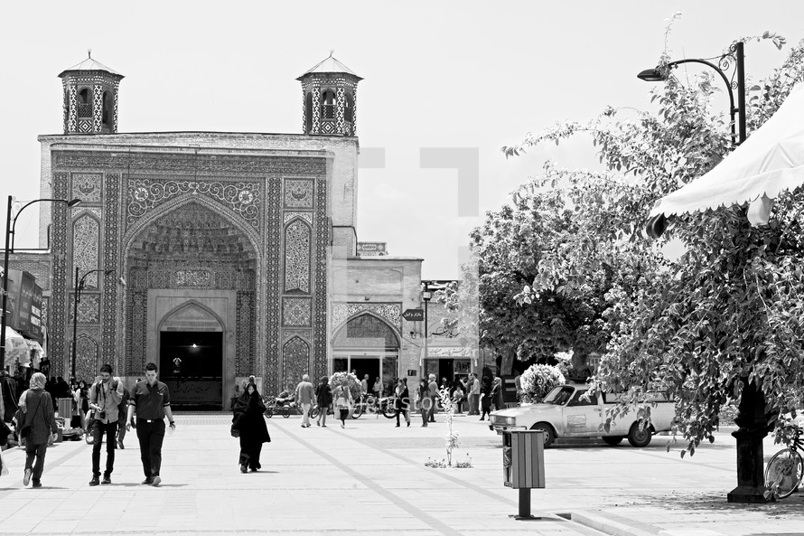 people walking through a courtyard towards a mosque in Iran 