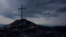A single wooden cross on a rocky mountain.