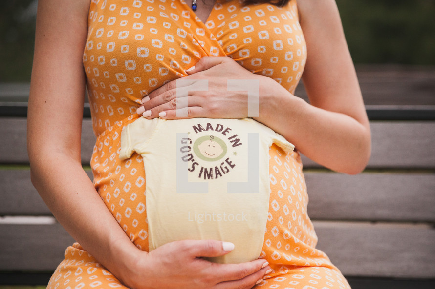 pregnant woman with a onesie that reads made in God's image 