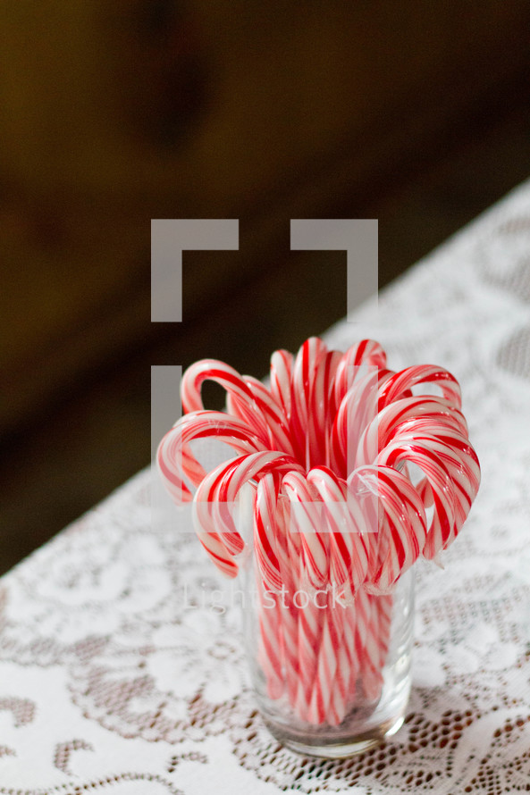 candy canes in a glass on a lace tablecloth 
