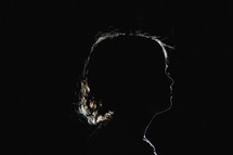 side profile silhouette of a girl child in a dark room 