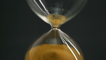 close up of sand pouring through an hourglass