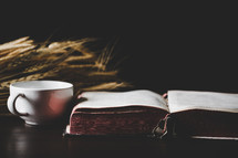 Bible and a mug and wheat on a table