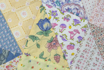 Closeup of part of a vintage patchwork quilt with triangles of floral pattern prints