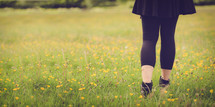 girl walking through a field of yellow wildflowers 