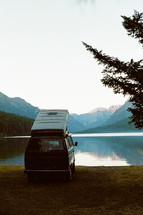 van with pop-up camper parked by a lake