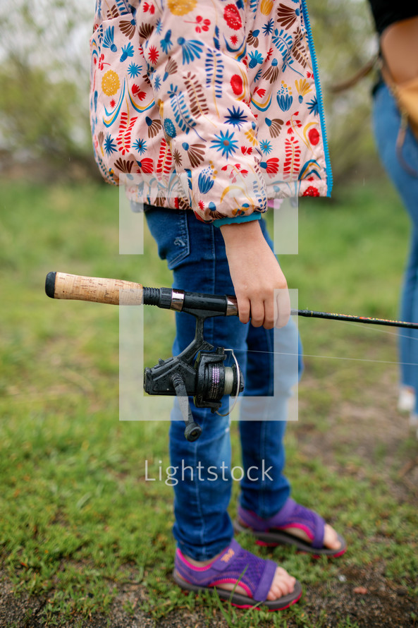 Little girl carrying a fishing pole 