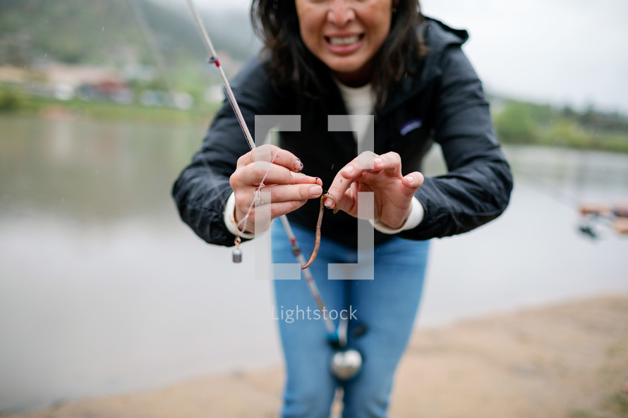 Mom putting a worm on the hook of a fishing line 