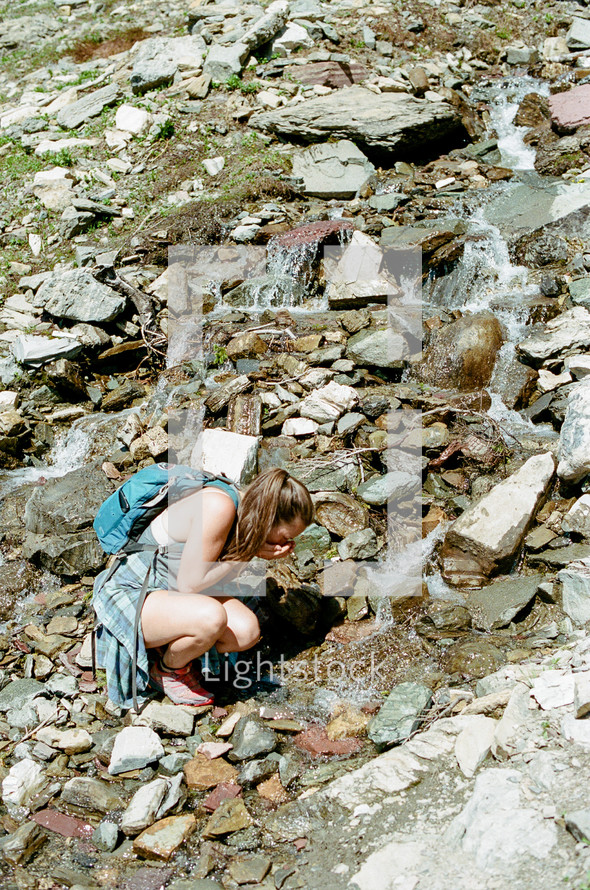 a woman drinking fresh water from a mountain spring 