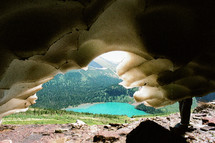 view of a turquoise pond through a frozen cave 