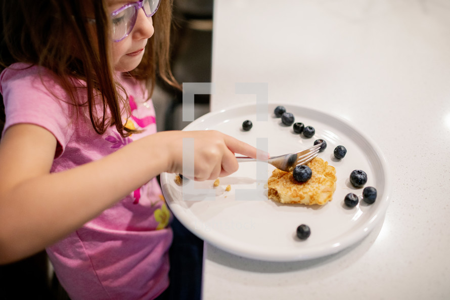 Little girl eating pancakes for breakfast 